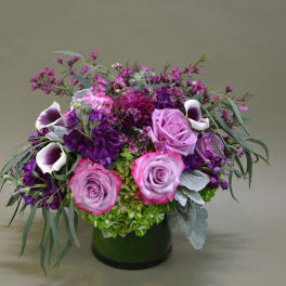 Purple and pink floral arrangement in a dark vase