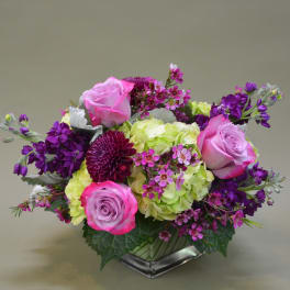 Pink roses and purple flowers arranged in a low vase