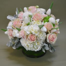 Round bouquet of pink roses and white flowers in a green vase
