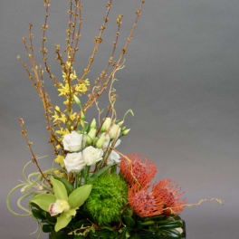 Tall floral arrangement with white blooms, yellow accents, and red pincushion flowers in a green vase
