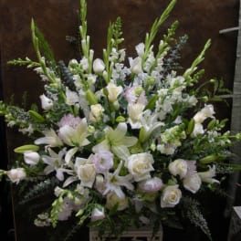 Large white floral arrangement with lilies and roses on a stand