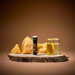 Lip balm, two small glass jars, and amber stones on a wood slab