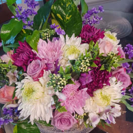 Mixed bouquet of pink, white, and purple flowers in a low container