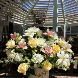 Yellow and white roses with pink flowers in a white vase
