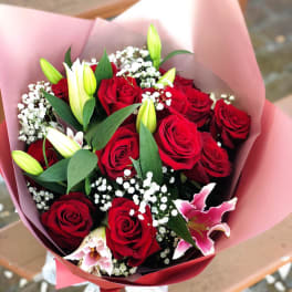 Bouquet of red roses and pink lilies wrapped in pink paper