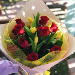 Bouquet of red roses and yellow tulips wrapped in pink paper