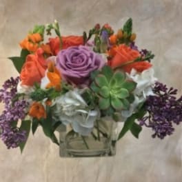 Mixed bouquet with roses, hydrangeas, and succulents in a clear vase