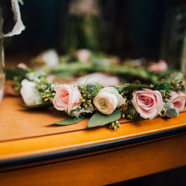 Pink and white floral crown with roses and ranunculus on a table