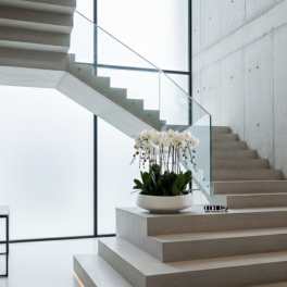 White orchid arrangement in a shallow white bowl on a staircase landing