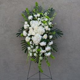 White floral standing spray on an easel with green accents
