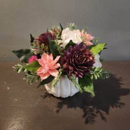 Artificial floral arrangement in a white pumpkin-shaped container