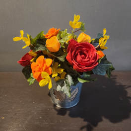 Small arrangement of red, orange, and yellow flowers in a metal pot