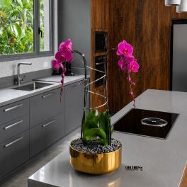 Potted orchids with bright pink blooms in a gold container on a kitchen island.
