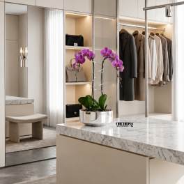Purple orchids in a silver pot on a marble island in a modern closet