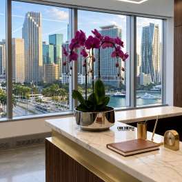 Potted purple orchid arrangement in a metallic planter on a marble desk
