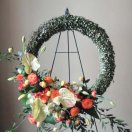 Floral wreath on a metal stand with orange and cream blooms