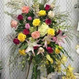 Tall floral spray with roses and lilies in pink, yellow, and white