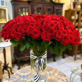 Large bouquet of red roses in a clear glass vase with a striped ribbon