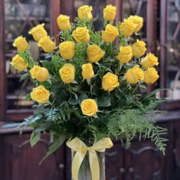 Yellow roses arranged in a clear glass vase with a ribbon