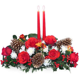 Low centerpiece of red roses, white mums, pinecones and berries with two tall red taper candles