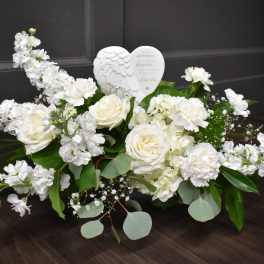 White floral arrangement with roses and carnations around a heart ornament