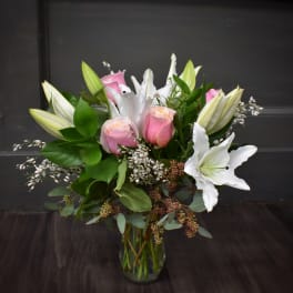 Pink roses and white lilies arranged in a clear glass vase