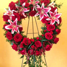 Heart-shaped wreath of red roses and pink lilies on a stand