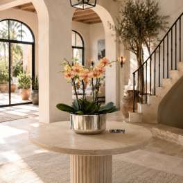 Potted orchid arrangement in a silver bowl on a round table