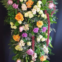 Tall standing floral spray with roses in pink, orange, and cream