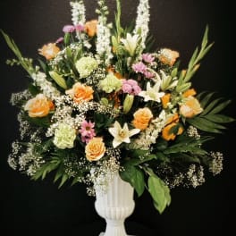Mixed floral arrangement in a white pedestal vase