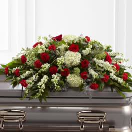 Red and white casket spray arranged on a silver metal casket