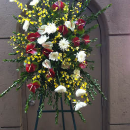 Standing floral spray with red anthuriums, white daisies, and yellow accents