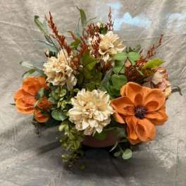 Orange and cream floral arrangement in a low container
