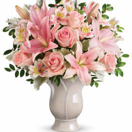 Pink lilies and roses arranged in a ceramic vase