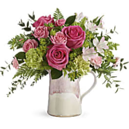 Pink roses and white lilies arranged in a ceramic pitcher
