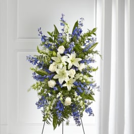 Tall standing floral spray with white lilies, white roses, and blue flowers