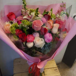 Bouquet of mixed roses and other flowers wrapped in pink paper