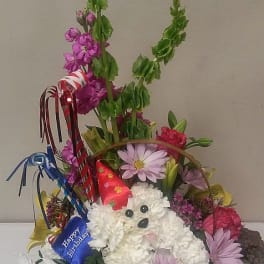 Basket arrangement with a white plush dog and colorful flowers