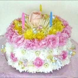 Round cake-shaped floral arrangement with pink and white flowers and candles