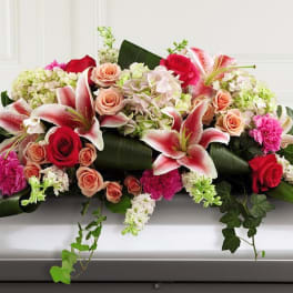 Casket spray with pink lilies, roses, and hydrangeas
