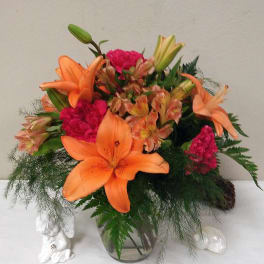 Orange lilies and pink carnations in a glass vase