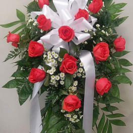 Standing spray of red roses with white ribbon and small white filler flowers
