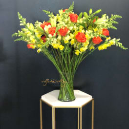 Mixed bouquet of red roses and yellow snapdragons in a glass vase