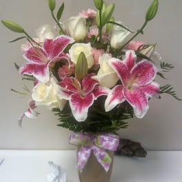 Pink lilies and white roses in a vase with a ribbon bow