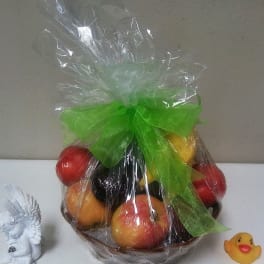 Wrapped fruit basket with a green bow and small decorative figurines