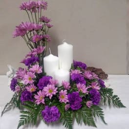 Purple and pink floral centerpiece with three white candles