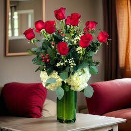 Red roses and white hydrangeas in a green glass vase