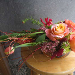 Orange and pink roses arranged in a low glass bowl