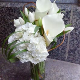 White calla lilies and hydrangeas in a glass vase