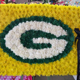 Yellow and green floral tribute with a white oval center and black ribbon